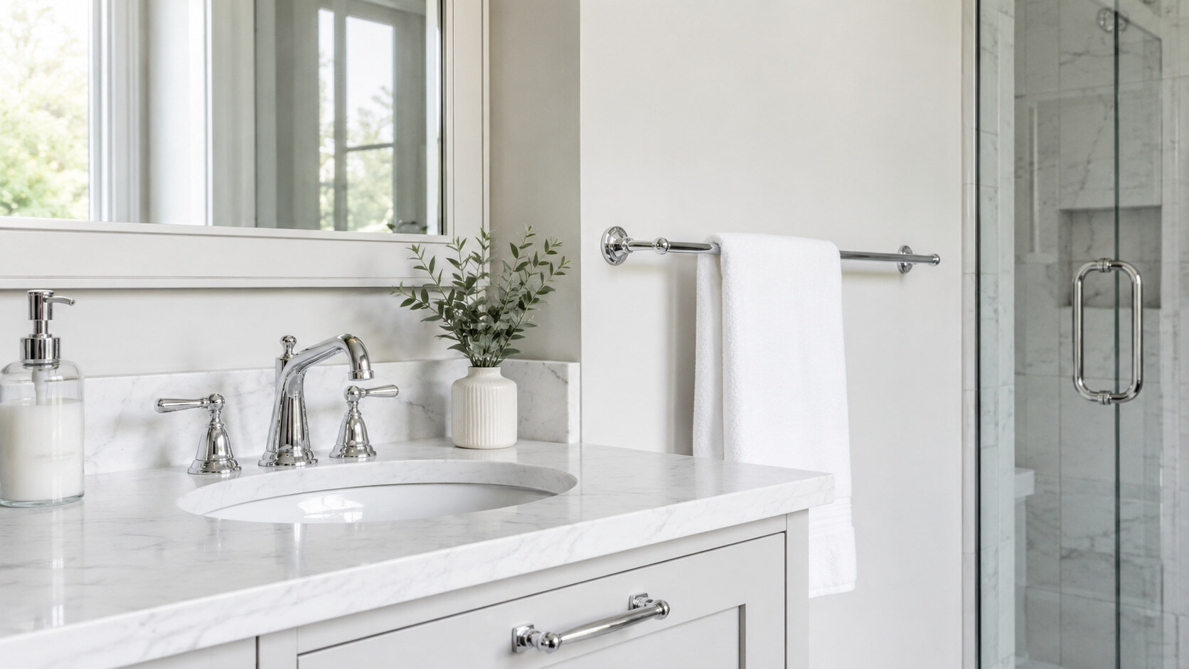A bathroom vanity with a marble countertop, chrome fixtures, and a white hand towel hanging on a rail.